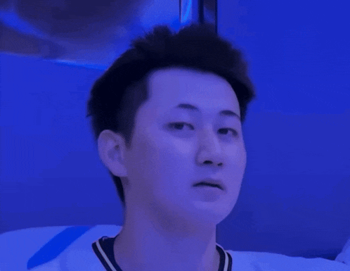 a man in a white shirt is making a funny face in front of a blue wall