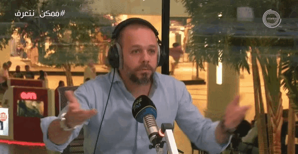 a man wearing headphones is talking into a microphone with a sign that says ' eon ' on it