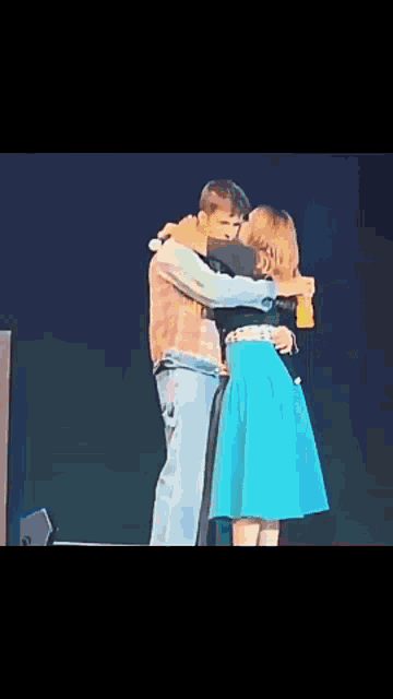 a man and a woman hugging on a stage .