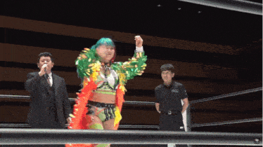 a woman with green hair stands in a wrestling ring with a referee