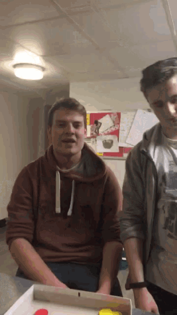 a man in a red sweatshirt is standing next to another man