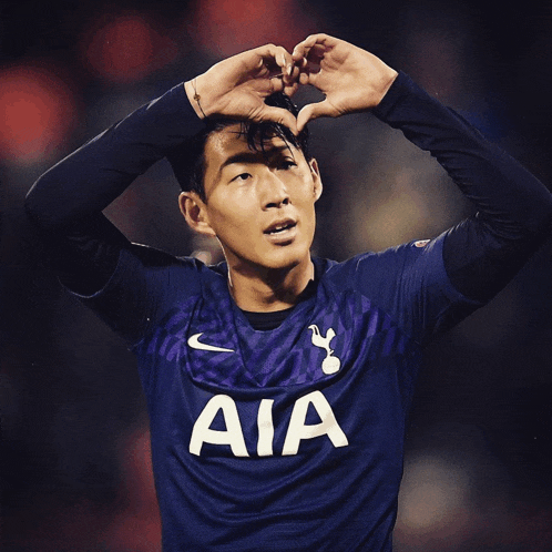a soccer player wearing a jersey that says aia makes a heart with his hands