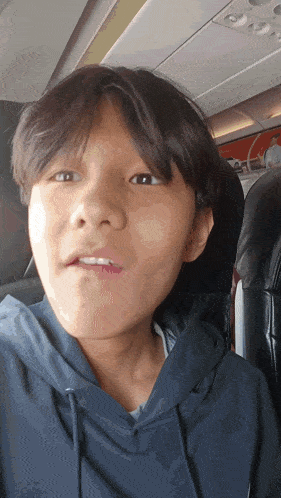 a young boy wearing a blue hoodie is sitting on a plane