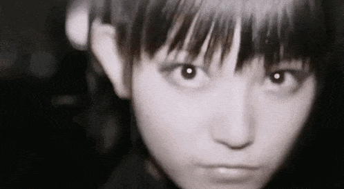 a close up of a girl 's face with a serious look on her face in a black and white photo .