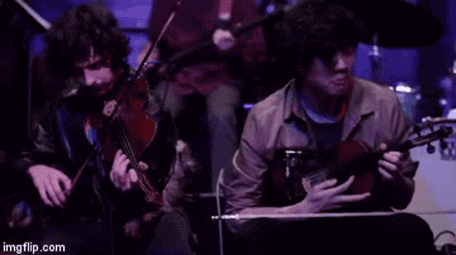a man playing a violin and another man playing a guitar in a band