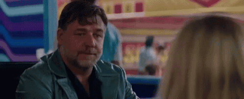a man in a blue jacket is sitting at a table with a woman .
