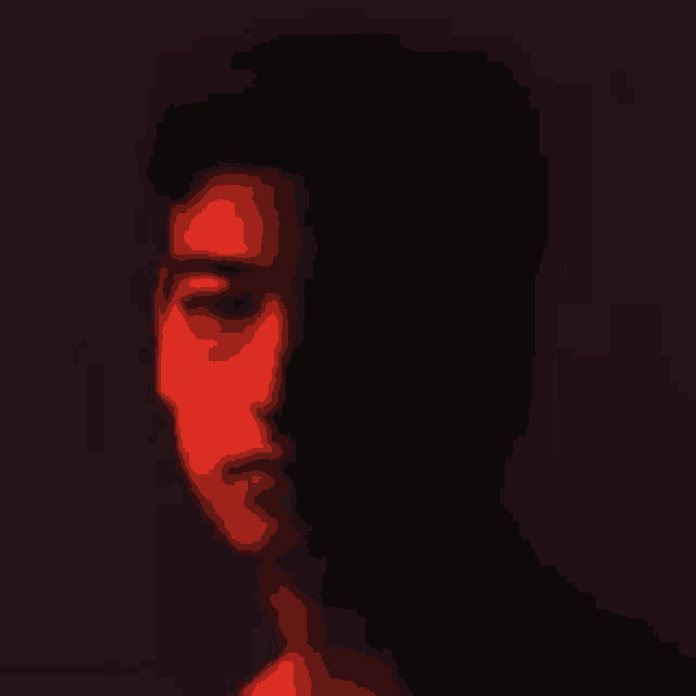 a close up of a man 's face in a dark room with a red light shining on it .