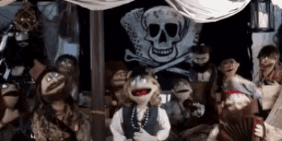 a group of pirate puppets are standing in front of a skull and crossbones flag .