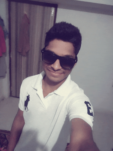 a young man wearing sunglasses and a white polo shirt with the letter e on the sleeve