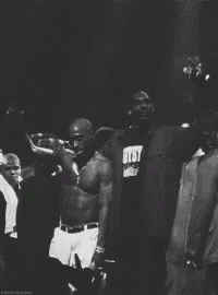 a black and white photo of a group of men including one wearing a shirt that says get