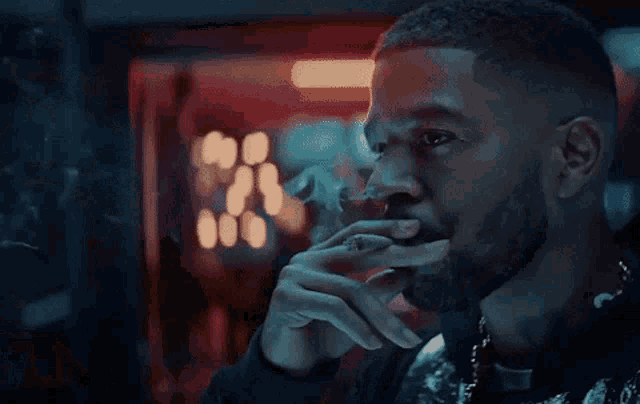a man with a beard is smoking a cigarette with smoke coming out of his mouth .