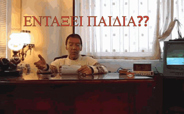 a man sits at a desk with the words " entaeei paiaia " written above him