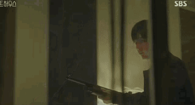 a man in a black jacket is holding a gun in a room .