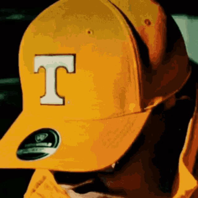 a man wearing a yellow hat with a white letter t on it