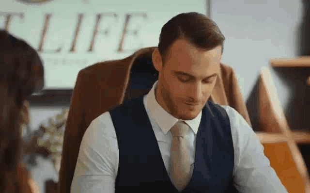 a man in a suit and tie is sitting at a desk with a woman .