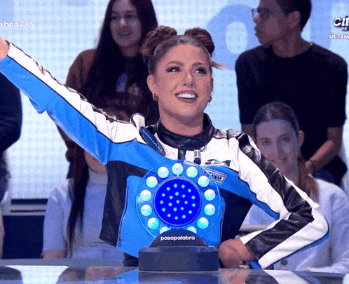a woman in a blue and white jacket stands in front of a passpalabra display