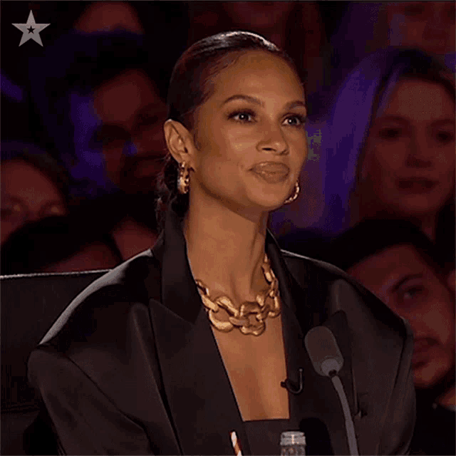 a woman sitting in front of a microphone with a star in the upper right corner