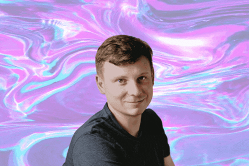 a man in a black shirt is smiling in front of a pink and blue background