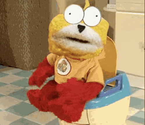 a stuffed animal is sitting on a potty wearing a superhero outfit