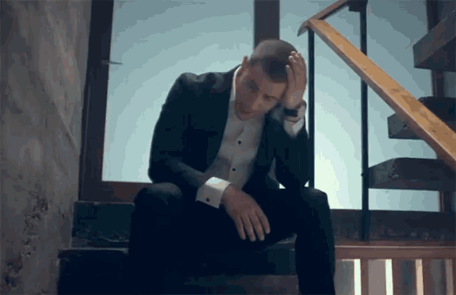 a man in a suit sits on a set of stairs