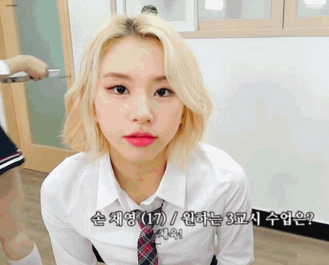 a girl with blonde hair is wearing a school uniform and a tie