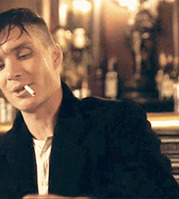 a man with a cigarette in his mouth is sitting at a bar .