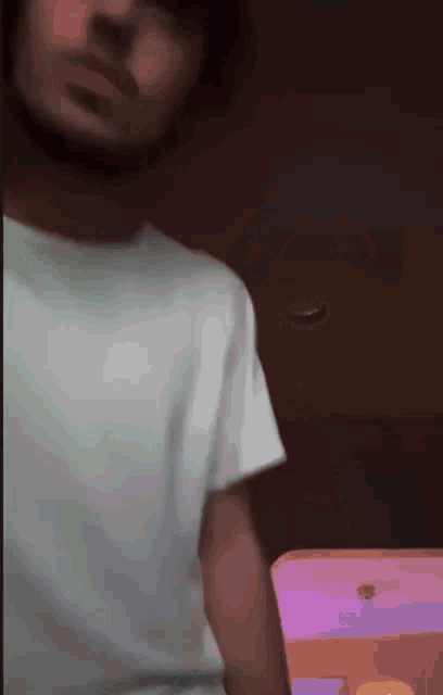 a man in a white shirt is holding a pink and purple object