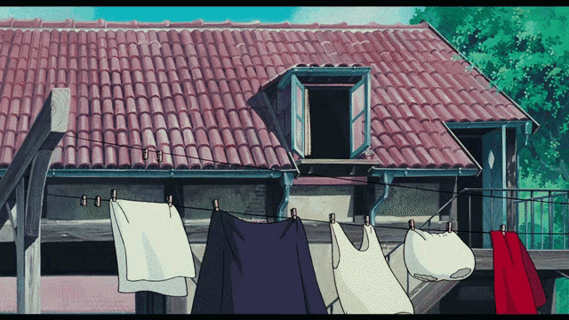 clothes hanging on a clothes line in front of a house with a red tile roof