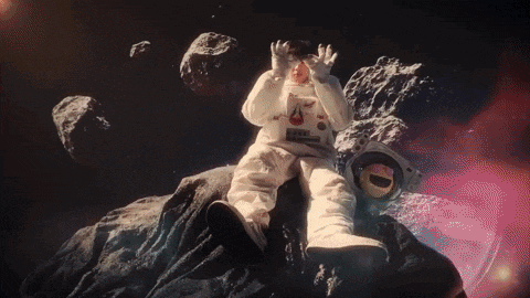 a toy astronaut is sitting on top of a rock .