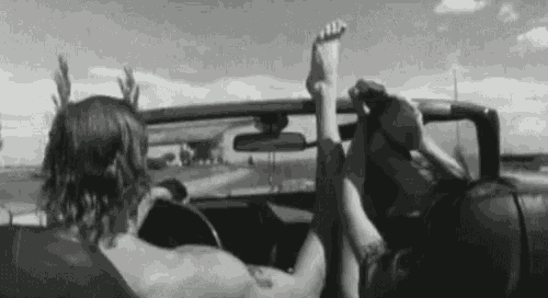 a man and a woman are sitting in a car with their feet up in the air .