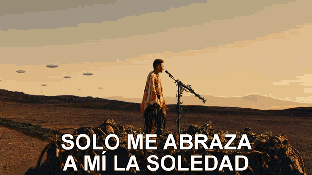 a man singing into a microphone in the desert with the words solo me abraza a mi la soledad above him