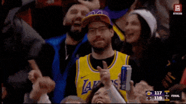 a man wearing a yellow lakers jersey holds a can of red bull