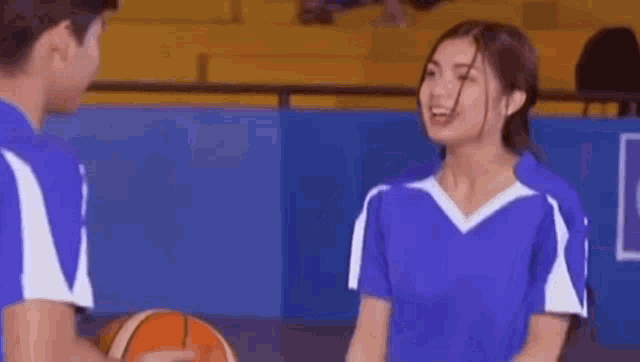 a man and a woman are standing on a basketball court holding a basketball .