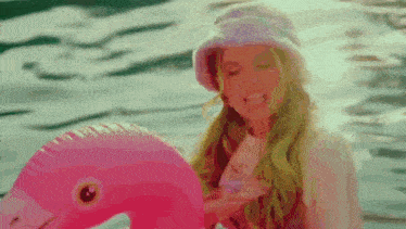 a woman is sitting on a pink flamingo in the water .