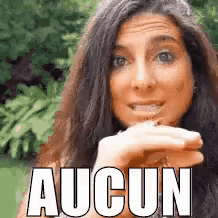 a woman with long hair is smiling and holding something in her hand with the words aucun written on it .