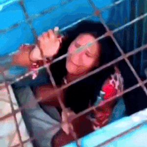 a woman is sitting in a cage with her eyes closed .