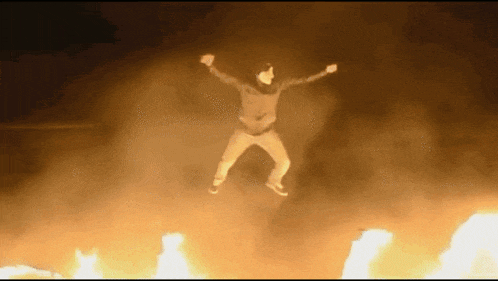 a person is jumping in the air in front of a fire .