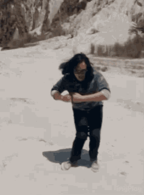 a man is dancing on a sandy hillside with imagesplay written in the lower right corner