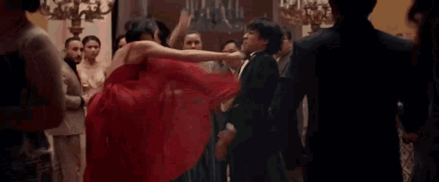 a woman in a red dress is dancing in a room with other people