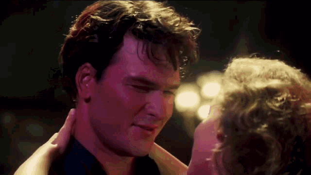 a man and a woman are dancing and the woman is touching the man 's neck