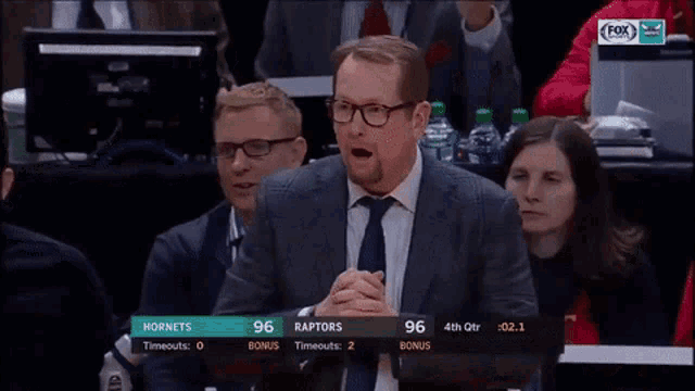a man in a suit and tie is watching a basketball game on fox network