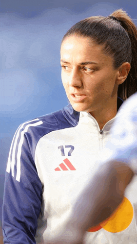 a woman wearing a white adidas jacket with the number 17 on the front