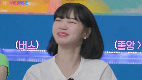 a woman with short black hair is smiling with her eyes closed while wearing a white shirt .