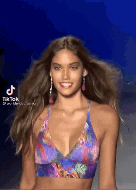 a woman is walking down a runway wearing a bikini top .