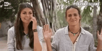 two women are standing next to each other and waving their hands .