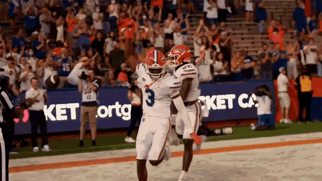 a football player with the number 3 on his jersey celebrates with his teammate