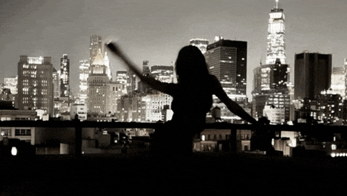 a woman is standing on a balcony overlooking a city skyline