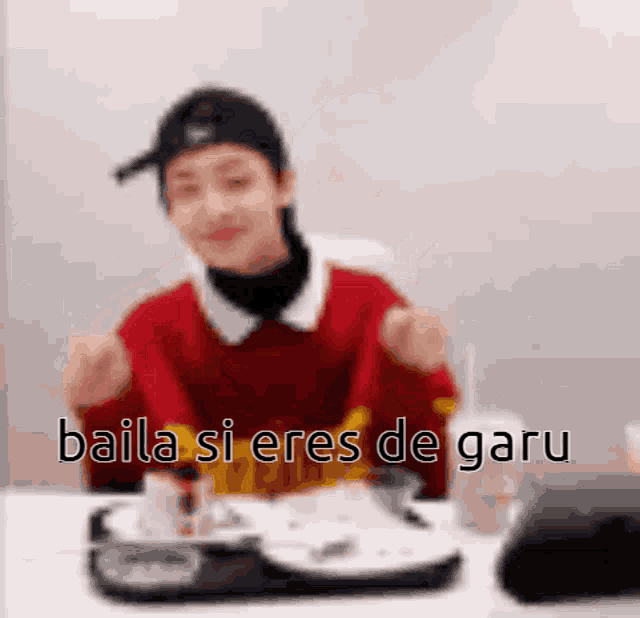 a blurry picture of a person sitting at a table with the words baila si eres de garu on the bottom