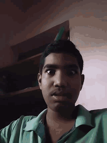 a young man in a green shirt is looking down at the camera