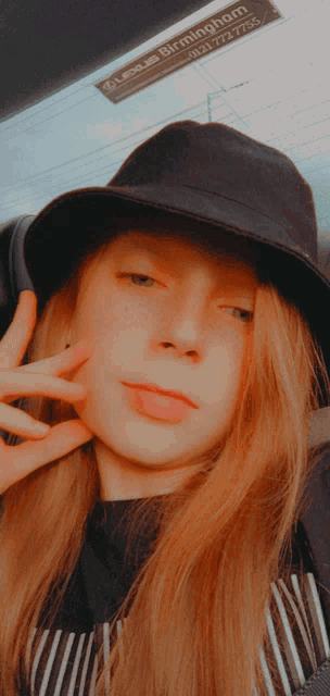 a girl wearing a black hat with a sign that says lexus birmingham